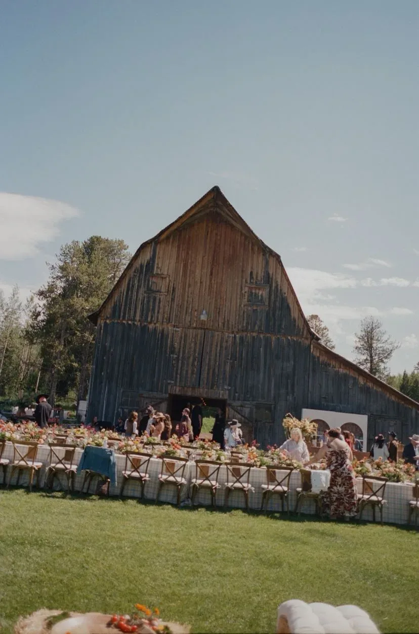 Long ranch banquet table set in front of a weathered barn