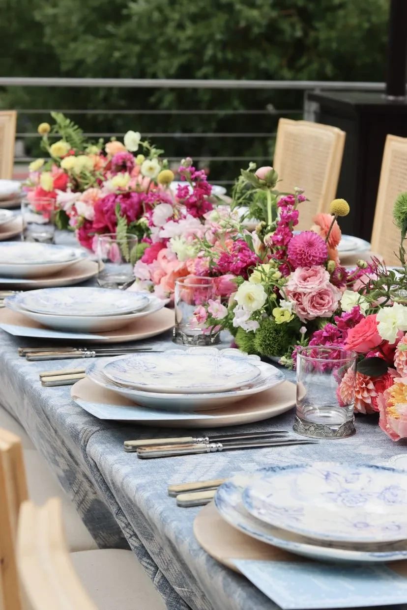 Close tablescape with blue-and-white plates and a pink and yellow floral runner