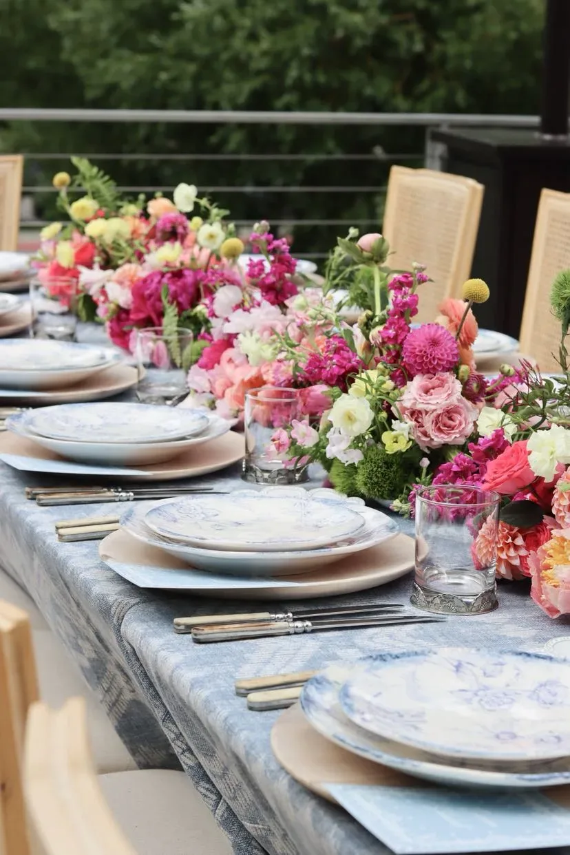 Close tablescape with blue-and-white plates and a pink and yellow floral runner