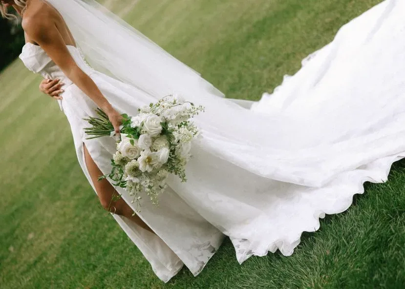 Bride in profile with a white bouquet and a long train