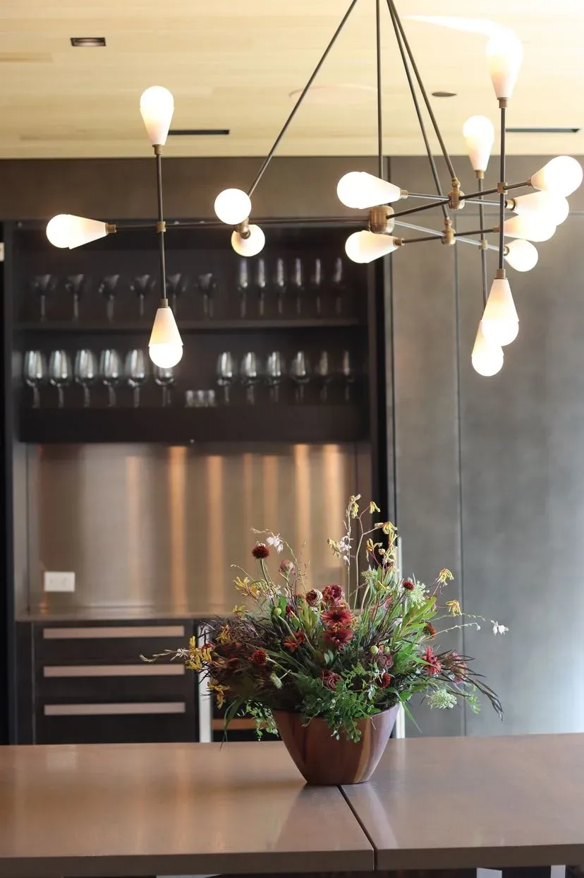 Garden-style arrangement in a wood bowl on a kitchen counter under a chandelier