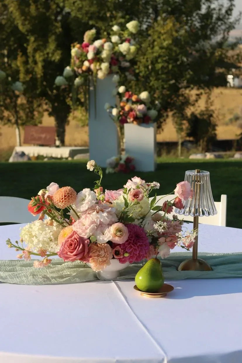 Round outdoor table with a dusty rose bowl, a small lamp and a pear