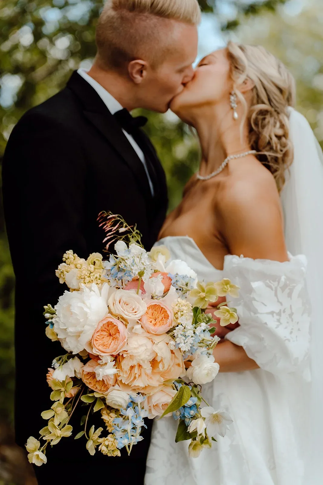 Bride holding a garden-style bouquet in soft peach and blue