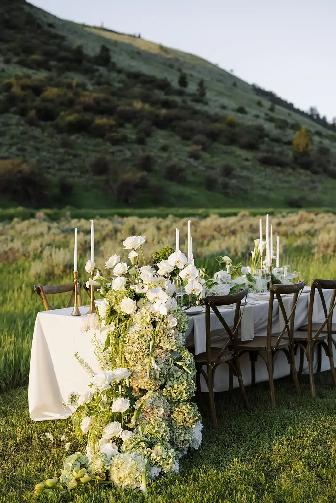 White floral installation flowing from an outdoor reception table