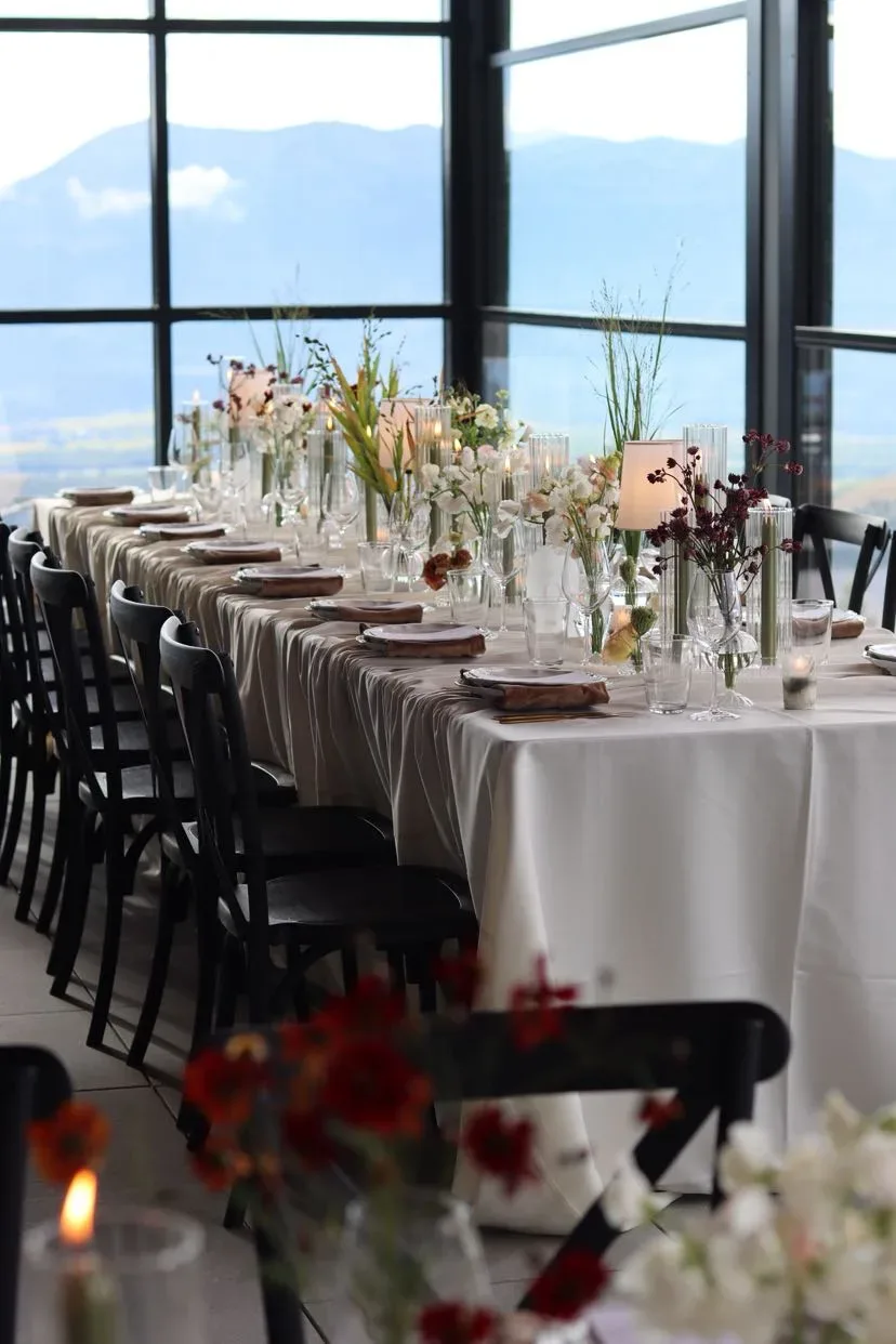 Long indoor table with tapers, grasses and mountain windows at the end of the room