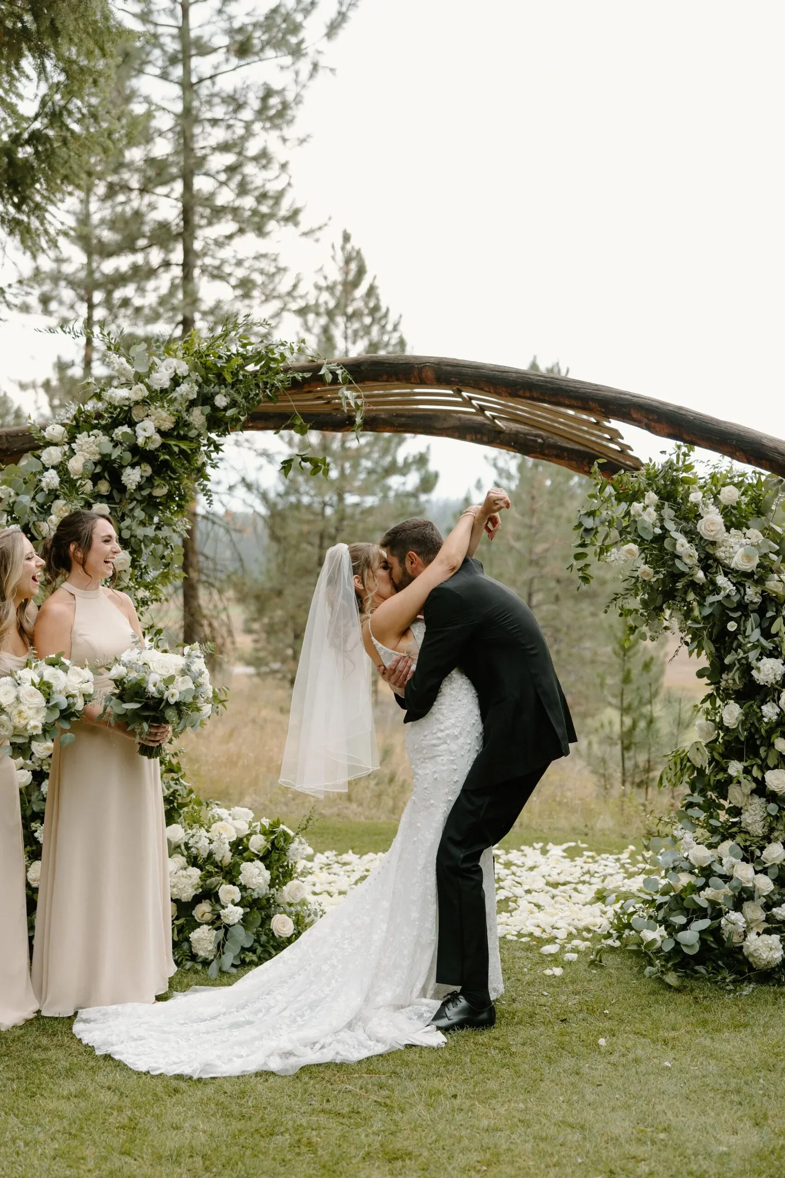 Newlyweds beneath a large woodland floral arch
